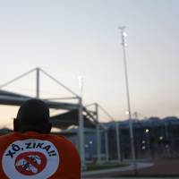 A worker from a public cleaning company wears a T-shirt that reads “Out Zika” before the inauguration ceremony of the common areas and the Live Site at the 2016 Rio Olympics park in Rio de Janeiro on Monday. Rio Zika probe points to Pacific island athletes bringing Asia strain in during 2014 canoe event