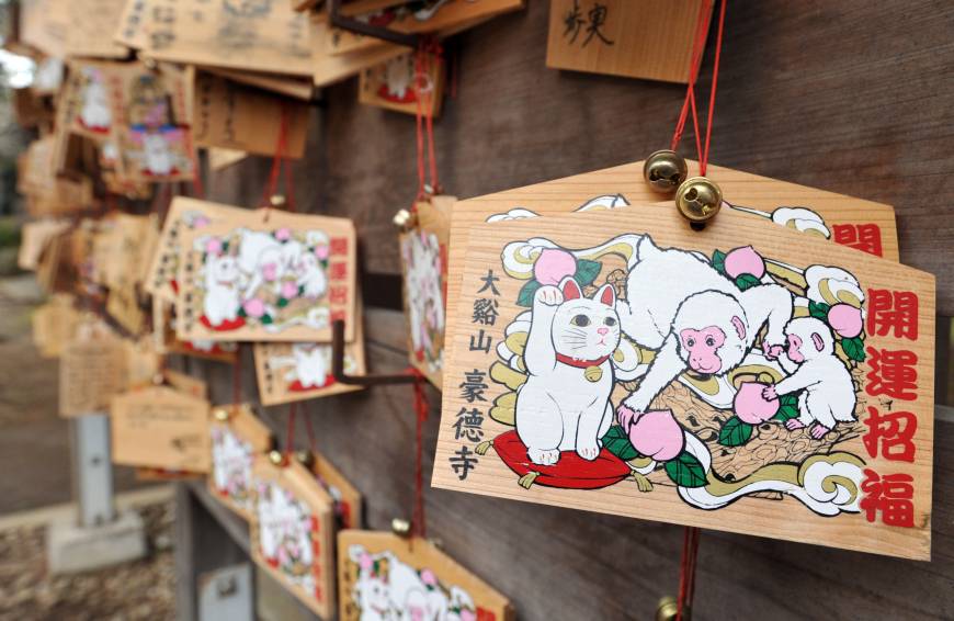 Wooden prayer tablets decorated with images of a beckoning cat and a monkey, this year