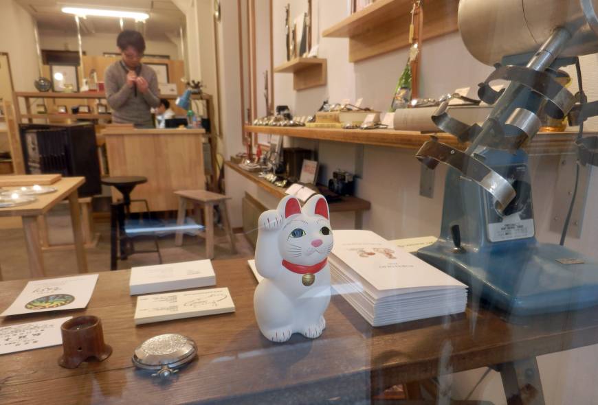 A maneki neko (beckoning cat) figure is displayed in the window of a store near Gotokuji Temple in Tokyo