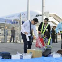 A passenger receives his luggage in the parking lot at Kumamoto Airport on Tuesday after arriving aboard an All Nippon Airlines flight from Tokyo. The airport is unable to provide baggage handling or security checks for departing fliers. Civilian flights resume to Kumamoto, but damaged terminal makes travel one-way