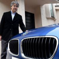 Businessman Randal Furudera poses beside his BMW M5 at his home in Tokyo on March 10. Luxury foreign cars find favor among Japan's rich