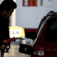 A customer fills up his vehicle at a self-serve gas station in Soka, Saitama Prefecture, in January 2013. Gas stations are closing down in many rural areas amid dwindling populations and a lack of next-generation operators. Residents rally to halt decline of rural gas stations