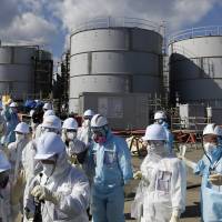 Journalists look at storage tanks filled with radioactive water at the tsunami-crippled Fukushima No. 1 nuclear power plant in the town of Okuma, Fukushima Prefecture, in February. Fukushima No. 1 plant's ice wall won't be watertight, says chief architect