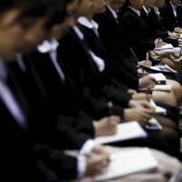 Female job seekers take notes as they attend an orientation session at a company booth during a job fair held for fresh graduates in Tokyo on March 20. Death by overwork on rise among Japan's vulnerable workers