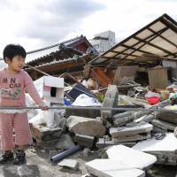 Rensuke Kimura, 5, helps his family hang out the laundry Thursday in front of their house in the town of Mashiki, Kumamoto Prefecture. The town was largely wrecked by this month's powerful earthquakes. PTSD sufferers increasing in quake-hit Kumamoto
