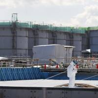 A worker takes notes in front of storage tanks for radioactive water at the Fukushima No. 1 nuclear plant on Feb. 10. Whether to release tritium from Fukushima No. 1 is a tricky problem