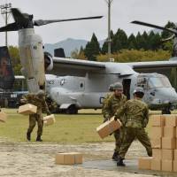 Ground Self-Defense Force troops carry emergency aid supplies from a U.S. Marine tilt-rotor Osprey aircraft as part of relief efforts in Minamiaso, Kumamoto Prefecture, on Monday. Japan on Monday enlisted U.S. help to airlift supplies to some of the 100,000 people whose homes were damaged or destroyed by earthquakes in the country's south, while rescuers struggled to find nine still missing after a massive landslide. U.S. Ospreys fly in relief as multiquake-hit Kumamoto rocks to new M5.8 aftershock