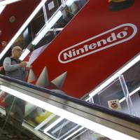 A shopper riding an escalator passes the Nintendo logo at an electronics store in Tokyo in March. Nintendo Co. now has its eye on the movie business for growth. Nintendo eyes filmmaking for growth after Mariners sale