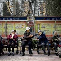 A group of elderly women rest in their wheelchairs at a residential compound in Beijing on March 31. As population ages, Beijing tracks its elderly as they take buses, go shopping