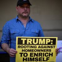 Aaron Black of Washington, D.C., participates in a demonstration urging U.S. Republican presidential candidate Donald Trump to make public his tax returns, outside his unfinished new hotel on Pennsylvania Avenue in Washington on Tuesday. Bernie barnstorms but Clinton targets Trump, hits his hope to profit from housing collapse