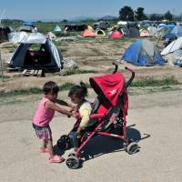 Childrens play with a stroller in front of tents in the refugee camp at the Greek-FYR of Makedonia border near the village of Idomeni on Monday. According to officials Greece will step up the evacuation of the squalid border camp Tuesday or Wednesday, as a major police operation is underway. Greece readies riot cops to clear squalid Idomeni camp as moms with babies look to God