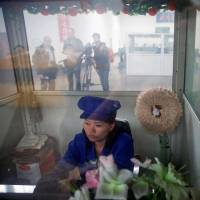 A worker sits in a booth as foreign reporters tour the Pyongyang 326 Electric Cable Factory on Friday. Paying for a can of peaches shows North Korean currency escaping regime's grip