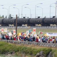 Anti-oil protestors walk past the Tesoro refinery rail yard in Anacortes, Washington, on Saturday. The protests are part of a series of global actions calling on people to “break free” from dependence on fossil fuels. Police arrest 52 climate activists blocking railroad near Washington refineries