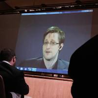 Former National Security Agency contractor Edward Snowden speaks via video conference to people in the Johns Hopkins University auditorium in Baltimore on Feb. 17. Snowden files set for wider release as more news organizations given access