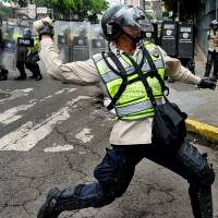 Policemen clash with demonstrators protesting new emergency powers decreed this week by President Nicolas Maduro in Caracas on Wednesday. Public outrage was expected to spill onto the streets of Venezuela Wednesday, with planned nationwide protests marking a new low point in Maduro's unpopular rule. Protesters demand president's ouster, food, as Venezuela crisis deepens, 700% inflation looms