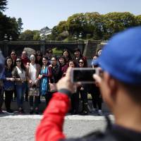 Chinese tourists pose for a photograph outside the Imperial Palace in Tokyo on April 15. Japan's tourism sector evolving but needs more work, cultural heritage expert says