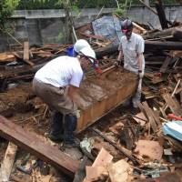 Rescuing memories: Shaun O'Dwyer (left) and other volunteers extract a chest containing photo albums and other valuables from the ruins of a house in Mashiki, Kumamoto Prefecture, days after the quakes last month. Foreign volunteers helping to rebuild lives in Kumamoto