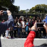 Tourists from China pose for a group photograph outside the Imperial Palace in Tokyo in April. Airbnb's 'master of disaster' comes to Tokyo as regulations loom