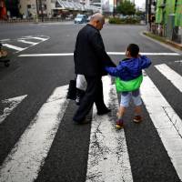 A man and his grandchild walk onva street at Tokyo's Sugamo district, an area popular among the Japanese elderly, Wednesday. Death and inheritance taxes: Japan's financial advisory firms enter the delicate but bountiful fray