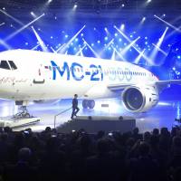 Russian Prime Minister Dmitry Medvedev walks to speak at the unveiling ceremony of the new passenger jet MC-21-300 at an Irkut Corporation assembling plant in Irkutsk, Russia, Wednesday. Made-in-Siberia: Russia boasts 'cool' new midrange jetliner to vie with Boeing, Airbus