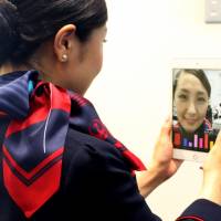 A Japan Airlines flight attendant checks her smile using a tablet device installed with a Shiseido app. The cosmetics firm says it has come up with a system to rate a person's smile by measuring facial movements. Cosmetics firm Shiseido rolls out smile-rating app