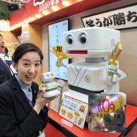 A woman shows a toy robot with an alarm clock, named Baku Shotaro, at the International Tokyo Toy Show in Koto Ward on Thursday. The robot made by Takara Tomy entertains users with a variety of jokes. Technology is the name of the game at International Tokyo Toy Show
