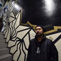 Painting the town: Artist Kohei Yamano, better known as Bakibaki, poses with his art in Tokyo. Street artists in Japan try to wipe out conservative views toward graffiti