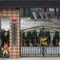 Children walk out from the Beijing No. 2 Experimental School near a tarp covering what used to be the running track, in Beijing on Thursday. China factories closed over toxic school tracks scare