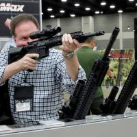James Bell from Nashville, Tennessee, looks over rifle scopes from Burris Riflescope at the National Rifle Association's (NRA) annual meetings and exhibits show in Louisville, Kentucky, May 21. NRA blames gun mayhem on White House failure to stop 'radical Islamic terrorists'
