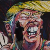 A man takes pictures of a graffiti of Republican presidential candidate Donald Trump in Barcelona, Spain, on Tuesday. Meryl Streep dons Donald look for Big Apple gala nominee shtick