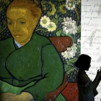 Visitors stand before an image of Van Gogh’s painting “La Berceuse (Augustine Roulin), December 1888” of a woman rocking a cradle, at a press event for the world premiere of the “Meet Vincent Van Gogh” exhibit in Beijing on Wednesday. The exhibit, organized by curators at the Van Gogh Museum, draws on the artist’s personal mementoes and artwork to present his life. It will open on Saturday. Newly discovered Van Gogh sketchbook to be published in November