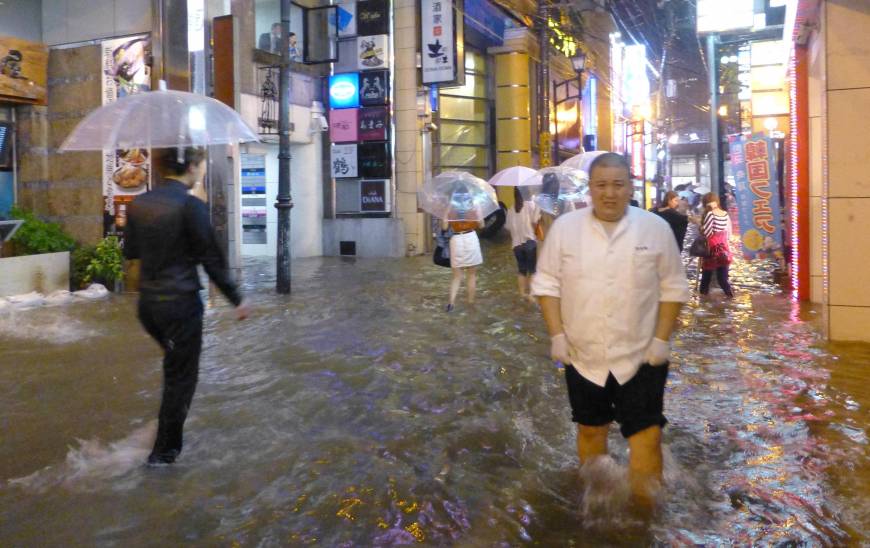 People walk on the streets of Nagasaki Monday night as torrential rain flooded wide parts of the prefecture and elsewhere in Kyushu. | KYODO