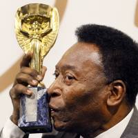 Brazilian soccer legend Pele kisses his replica of the Jules Rimet Trophy in London on Wednesday. Pele cashes in on memorabilia