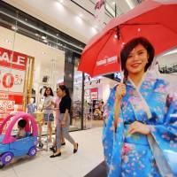 Shoppers pass sale signs at an Aeon Co. mall in Hanoi's Long Bien district on Thursday. As Japan grays, retailers covet youthful masses in Vietnam