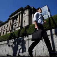 A man trots past the Bank of Japan headquarters in Tokyo on Friday. The central bank has announced it will almost double its annual purchases of exchange traded funds to ¥6 trillion from the current ¥3.3 trillion to boost stimulus. BOJ eases further, signals policy review as inflation target eludes