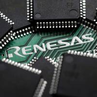The Renesas Electronics Corp. logo is seen on a computer board while the company’s chips are arranged. The chip-maker is said to be considering outsourcing research overseas. Renesas embraces change with plans to outsource chip R&D