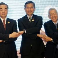Chinese Foreign Minister Wang Yi (left), Singapore Foreign Minister Vivian Balakrishnan (center) and Philippine Foreign Secretary Perfecto Yasay Jr. pose for a photo during the Association of Southeast Asian Nations-China Foreign Ministers' Meeting in Vientiane on Monday. China scores diplomatic victory, avoids criticism from ASEAN