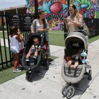 Two women walk Friday with their children in Miami's Wynwood neighborhood, where four people have become infected with the Zika virus. Florida resists federal help in investigating Zika outbreak