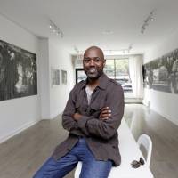 Gallery owner Louis Long poses among works by artist Dareece J. Walker in New York's Harlem neighborhood on Thursday. Harlem burgeons as an art gallery district