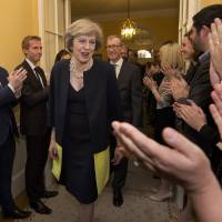Staff applaud as Britain's new Prime Minister Theresa May, and her husband, Philip, walk into 10 Downing Street after May met Queen Elizabeth II in Buckingham Palace, in central London, Wednesday. May takes U.K. helm, taps Johnson for top envoy, Hammond for finance