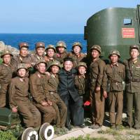 North Korean leader Kim Jong Un poses with soldiers during an inspection of an outpost on the Sea of Japan coast in this undated photo released July 7. Pyongyang says triple missile test simulated attack on South Korean ports and airfields