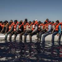 Refugees and migrants from Eritrea, Mali, Bangladesh and other countries wait on board a dinghy to be rescued Tuesday in the Mediterranean Sea, 27 km (17 miles) north of Sabratha, Libya. Mediterranean teams rescue 3,200 migrants, find 22 dead in bottom of dinghy