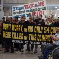 Police officers and firemen demonstrate at the international arrivals gate as they protest the government's delay in their salary payments at Tom Jobim International Airport in Rio de Janeiro Monday. Protesting Rio cops greet airport arrivals with 'Welcome to Hell' banners