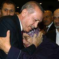 Turkish President Recep Tayyip Erdogan hugs a woman during an event in Ankara on Friday to honor those killed or wounded during the July 15 coup attempt. Erdogan eyes closing military schools, bringing armed forces under Defense Ministry control