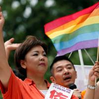 Kaori Sato, an independent candidate running in Sunday's Upper House election, holds a rainbow flag and waves as Hiroshi Taniyama (right) of the Nakano LGBT Network Nijiiro speaks during a campaign in Tokyo on July 2. Japan election manifestos free LGBT rights from political closet