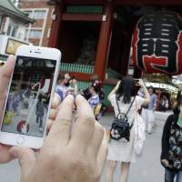 A man tries to catch a Pikachu character while playing Pokemon Go in front of Kaminarimon Gate at Sensoji Temple in Tokyo's Asakusa district on Friday. Japanese tourist sites on alert following 'Pokemon Go' launch