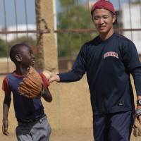 Japanese aid worker Ryoma Ogawa plays baseball with young Senegalese children on a field in the impoverished Oukam neighborhood of Dakar on July 13. JICA volunteer teaching Senegal's kids how to play sandlot baseball
