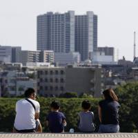 People sit on steps near the Tamagawa River in Futako Tamagawa, Setagaya Ward, on Sunday. As Japan's population slides, one mayor wrestles with overcrowding