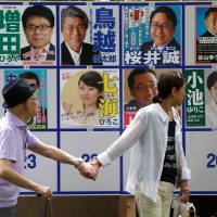 People walk past candidate posters for the Tokyo gubernatorial election on Sunday. Tokyo votes to elect new governor after scandals