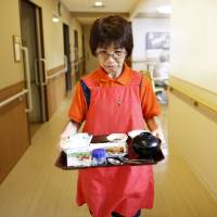 New responsibilities: Caregiver Sonoe Kudo carries dinner to a resident at a nursing home in Tokyo. Care for elderly relatives may become the legal duty of the family, reducing the government’s own public-welfare responsibilities. Constitutional change may target Japan's elderly